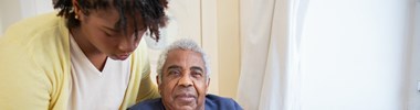 woman helping older man into chair