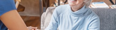 smiling older woman with glasses looking at paid care worker